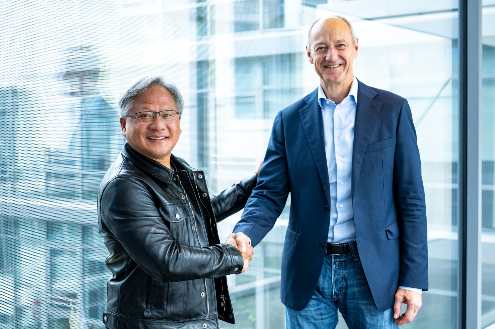 NVIDIA Founder and CEO Jensen Huang shakes Siemens CEO Roland Busch's hand as they discuss digital twin technology.