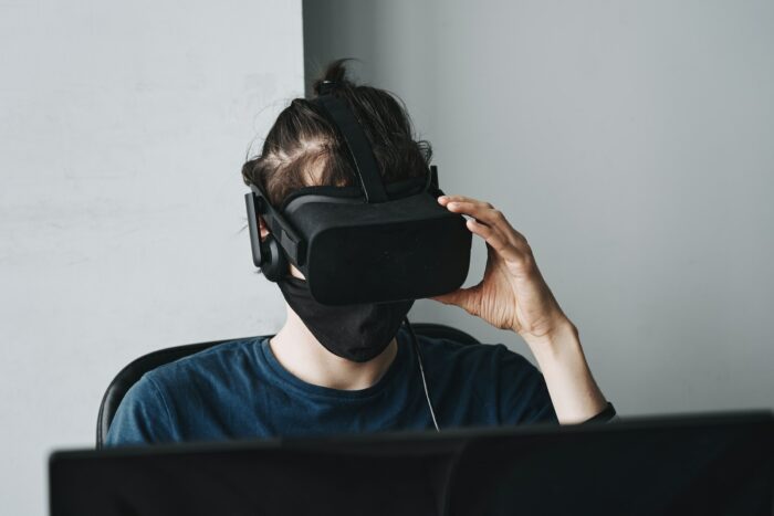 Man in blue crew neck shirt wearing black metaverse VR headset