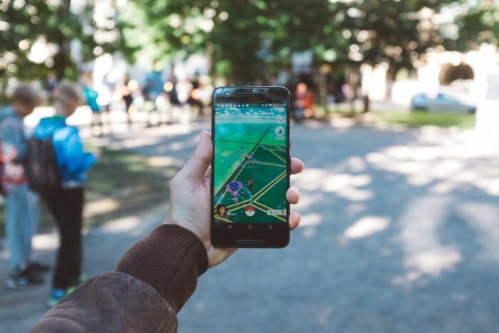 A person holds a smartphone while playing an outdoor augmented reality game called Pokemon Go.