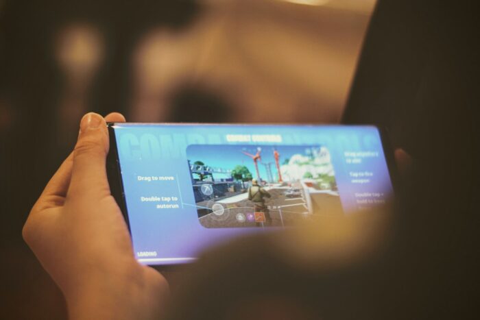 person holding smartphone with fortnite mobile on screen