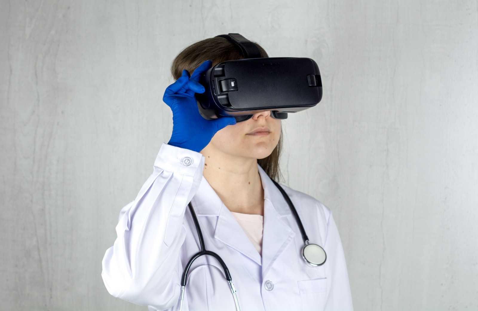 a woman in a white coat and blue gloves is wearing a virtual headset